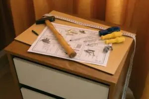 Home From above of wooden cabinet with drawers and paper instruction with tool to assemble it